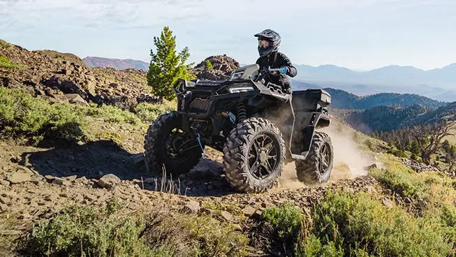 A rider on a Polaris Sportsman XP 1000 Ultimate ATV driving on a hillside.