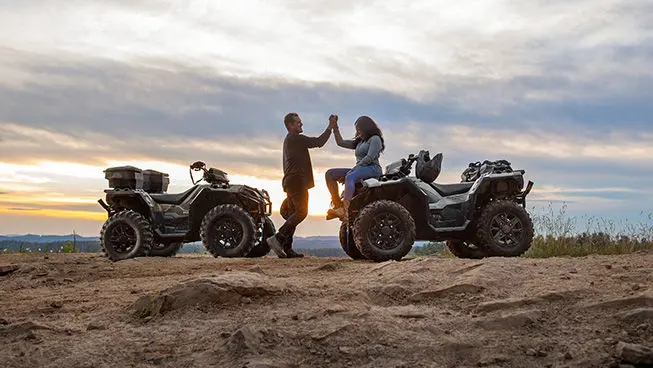 Two riders congratulating each other after a ride on their Polaris Sportsman XP 1000 ATVs.
