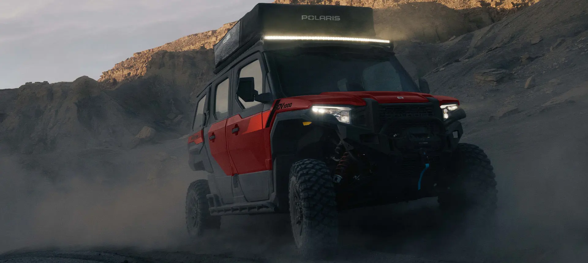 A Polaris XPEDITION ADV 5 NorthStar side-by-side with lights illuminated in the desert.