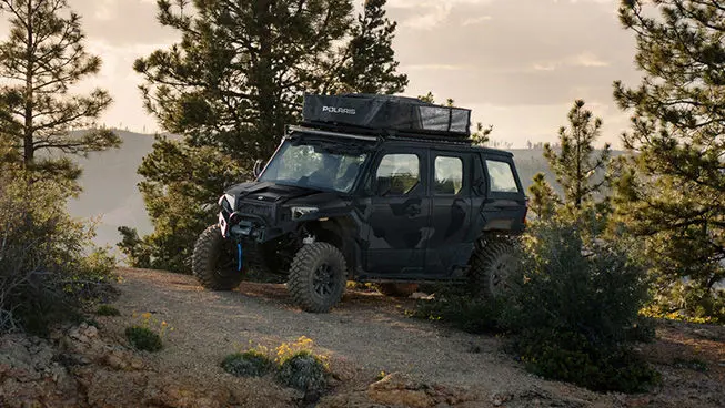 Side profile of a Matte Super Graphite  Polaris XPEDITION ADV 5 NorthStar parked on a hill.