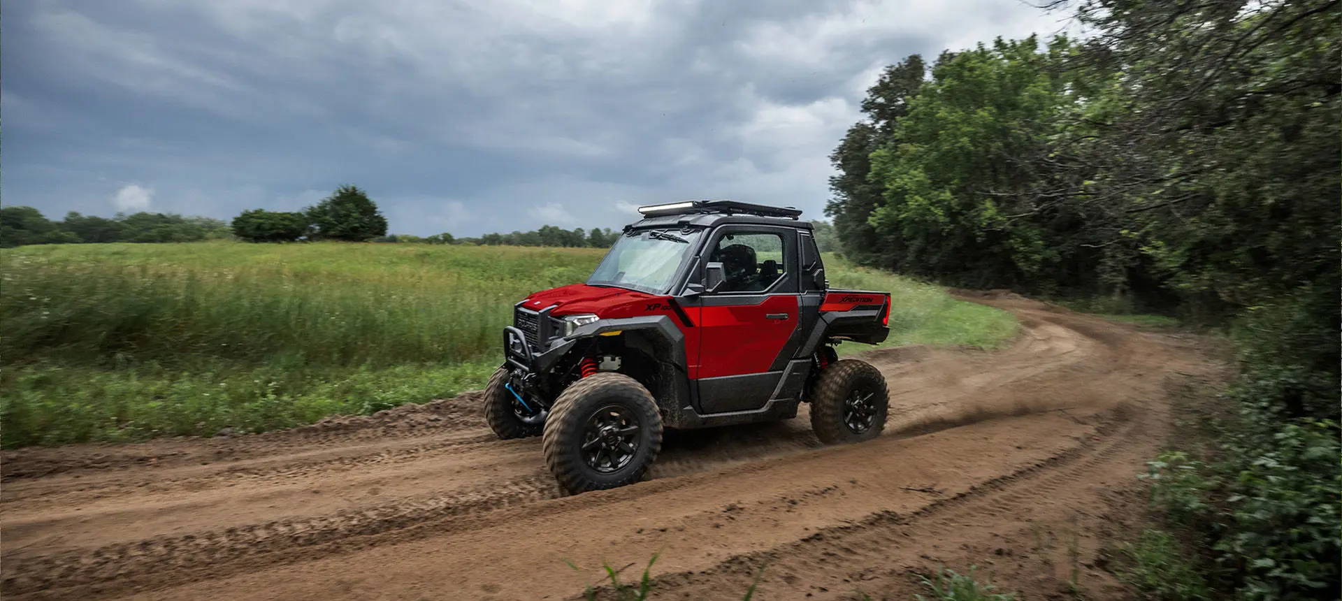 Side profile of a Performance Red Polaris XPEDITION XP side-by-side cruising on a trail.