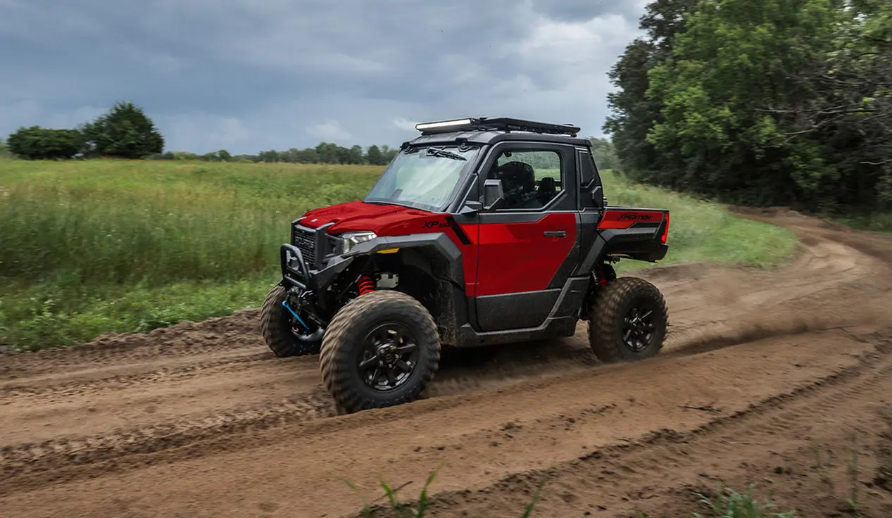 Side profile of a Performance Red Polaris XPEDITION XP side-by-side cruising on a trail.