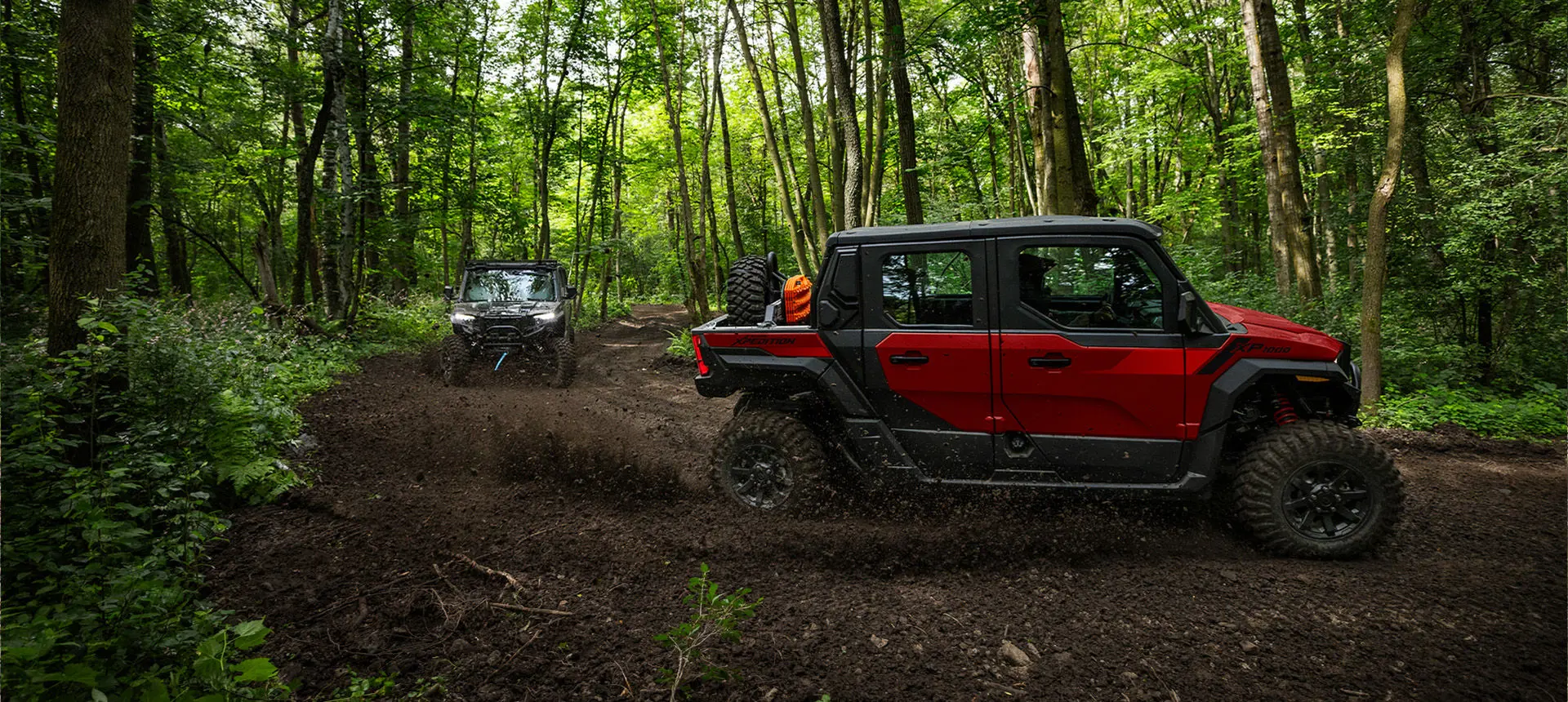 2 Polaris XPEDITION XP 5 NorthStar side-by-sides throwing dirt on a forest trail.