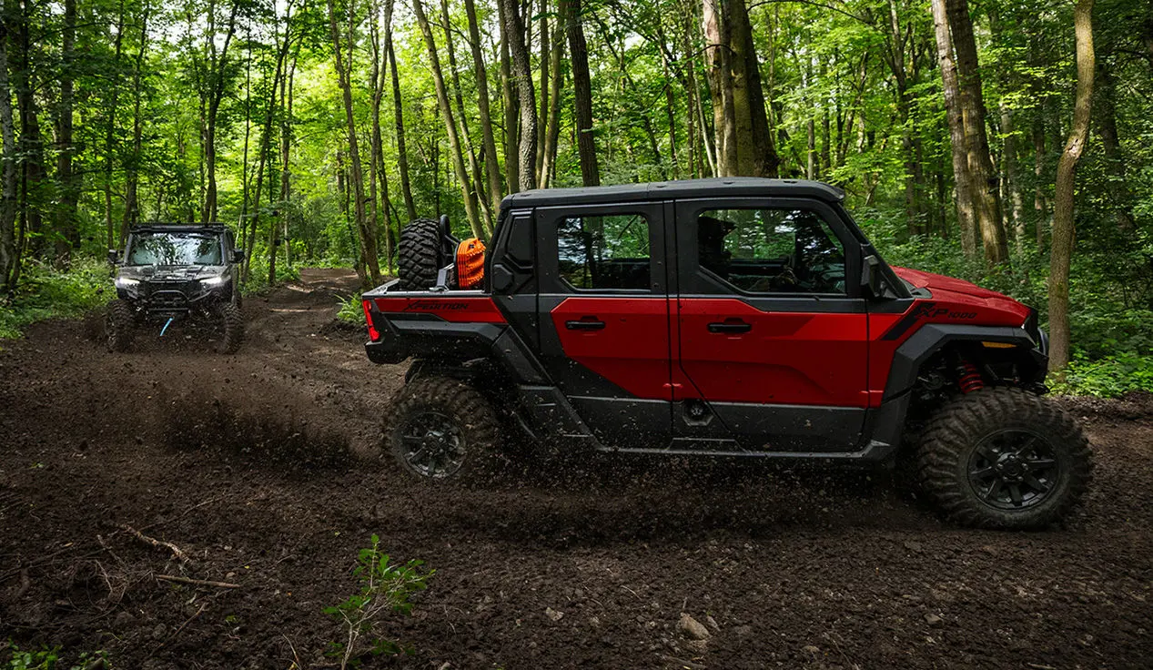 2 Polaris XPEDITION XP 5 NorthStar side-by-sides throwing dirt on a forest trail.