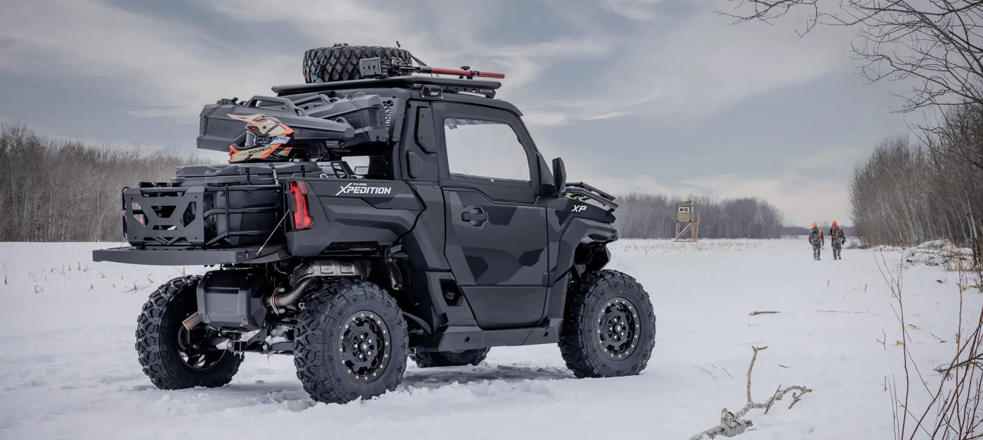 2 hunters walking away from a parked Matte Super Graphite Polaris XPEDITION XP NorthStar side-by-side.