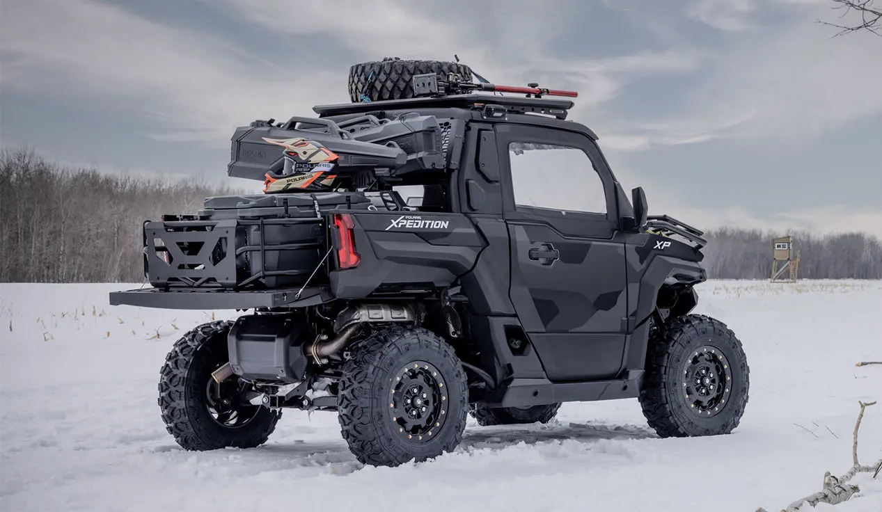 2 hunters walking away from a parked Matte Super Graphite Polaris XPEDITION XP NorthStar side-by-side.
