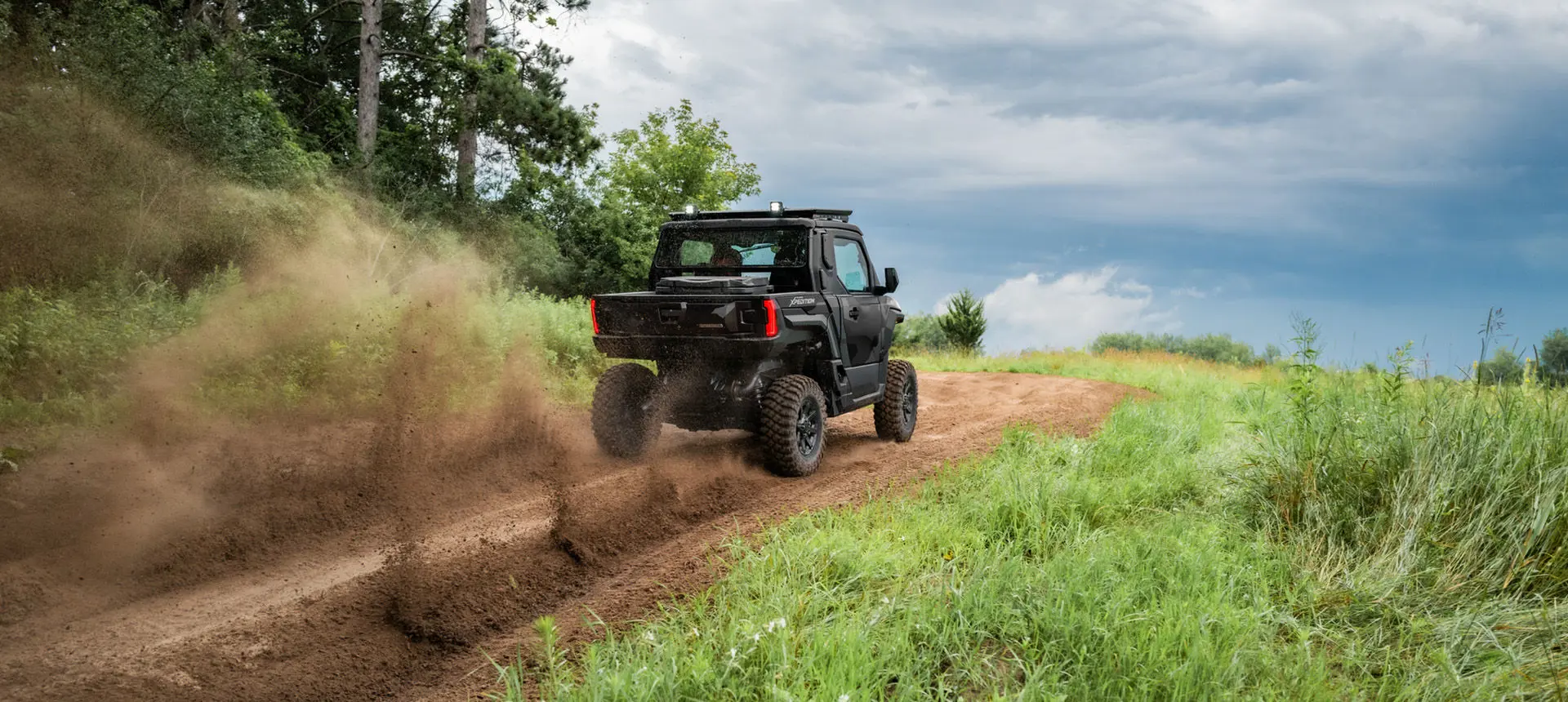 Rear view of a Matte Super Graphite Polaris XPEDITION XP NorthStar side-by-side driving on a trail.