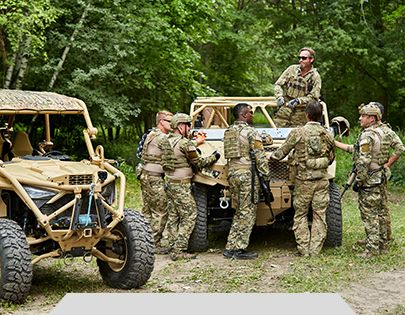 U.S. soldiers huddled around a Polaris Government & Defense vehicle.