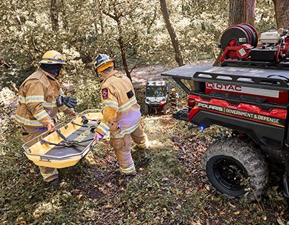 Fire fighters using the rescue skid from the cargo box of a Polaris RANGER UTV with Government & Defense packages installed.