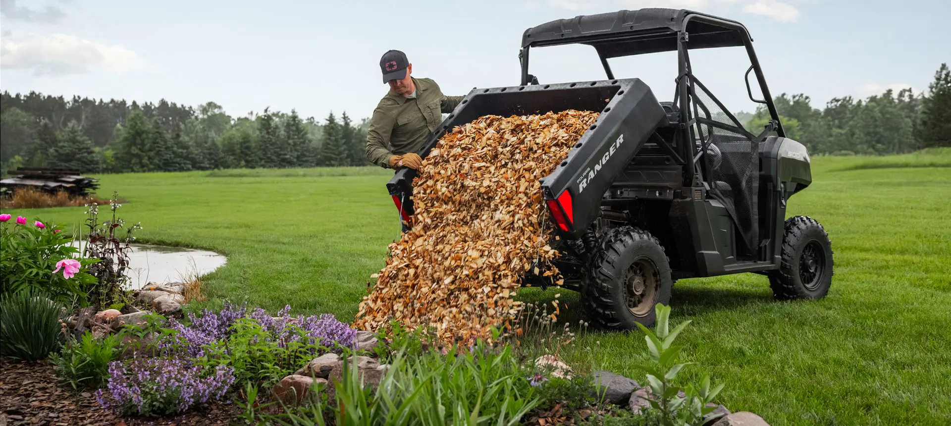 A man dumping mulch from the cargo box of his Polaris RANGER 500 UTV.