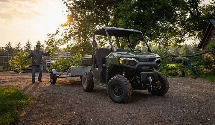2 men clearing a fallen tree and putting branches into the cargo box of their Polaris RANGER 500 UTV.