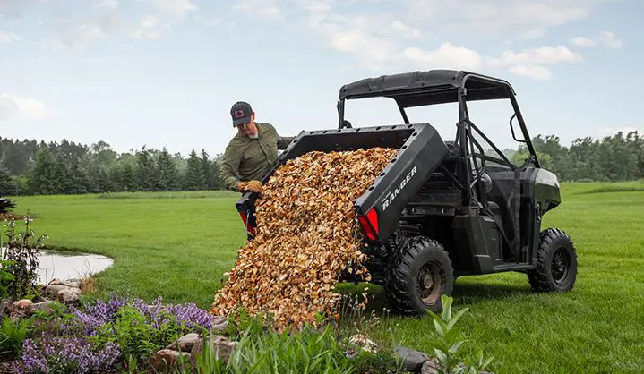 A man dumping mulch from the cargo box of his Polaris RANGER 500 UTV.