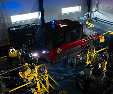 Polaris Government and Defense vehicle mounted to a vehicle durability test rig inside an engineering laboratory, simulating real-world terrain forces and chassis stress.