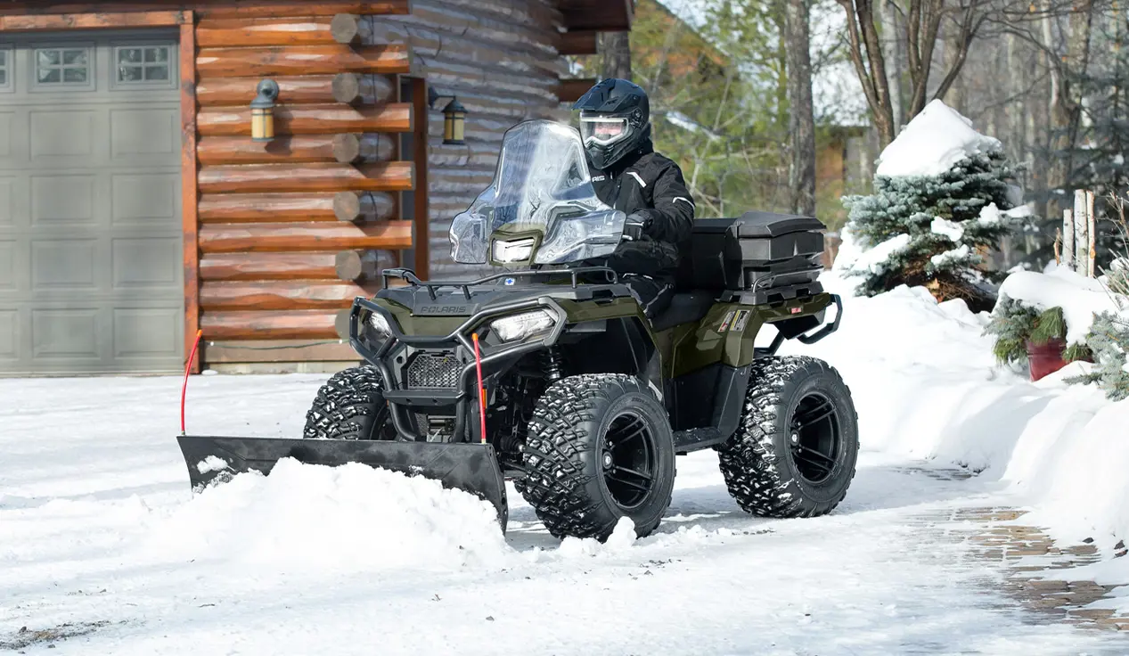 Person using a Polaris Sportsman ATV for snow removal, and grounds and facility operations.