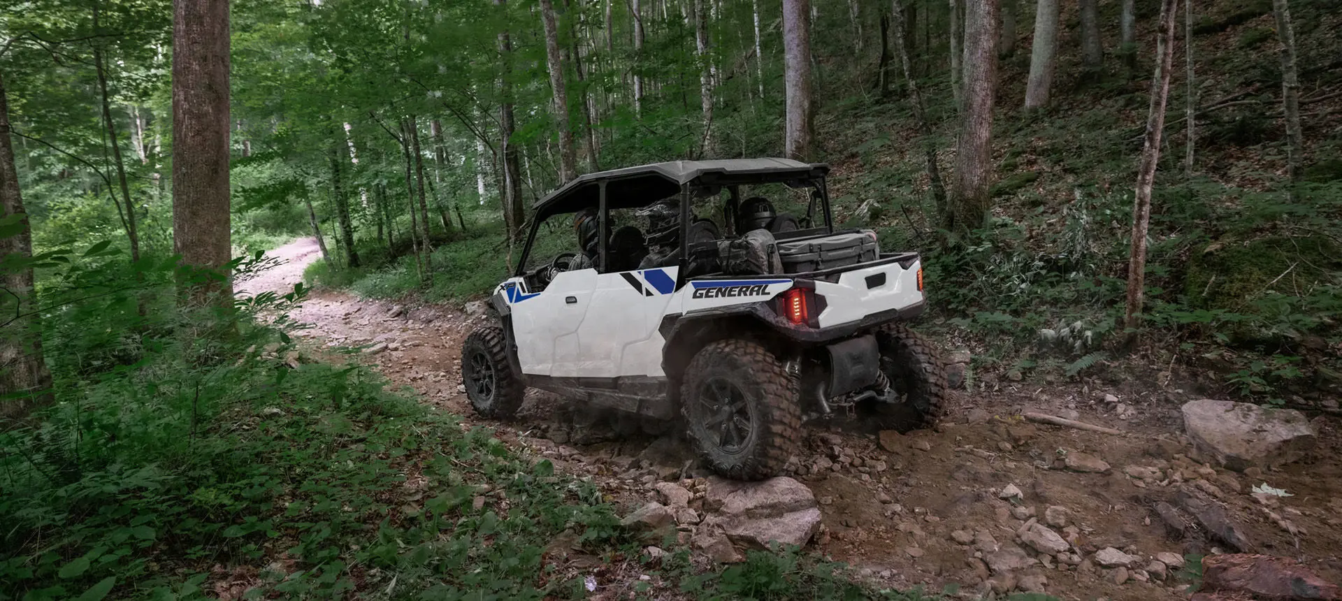 Polaris GENERAL XP 4 1000 side-by-side driving through the forest with a fully loaded cab.