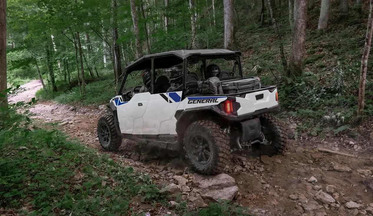 Polaris GENERAL XP 4 1000 side-by-side driving through the forest with a fully loaded cab.