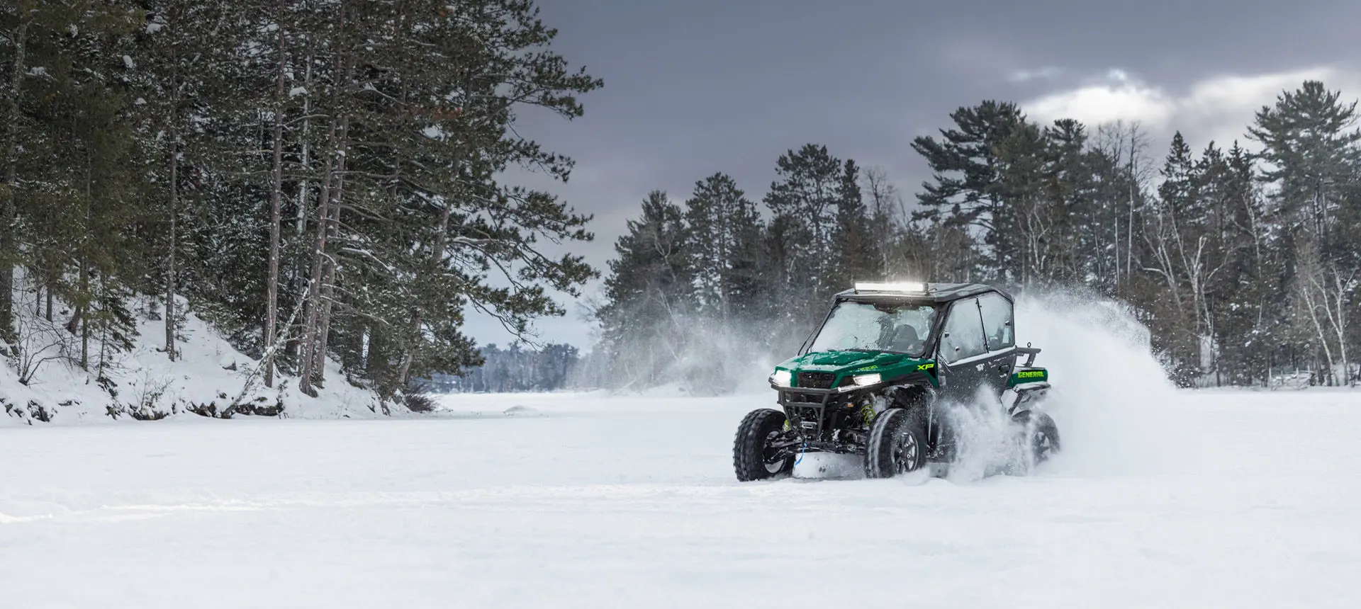 A Polaris GENERAL XP 1000 side-by-side with lightbar and full door accessories installed driving through a snowy field.