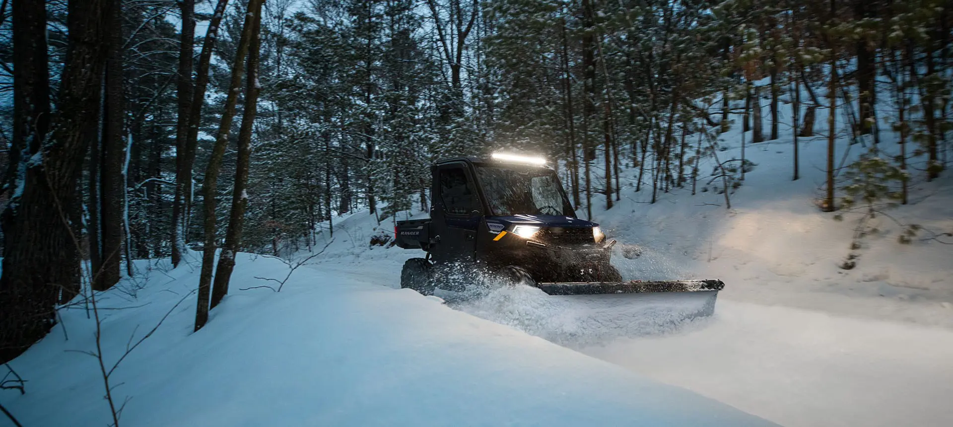 A Polaris RANGER 1000 UTV plowing snow in the winter.