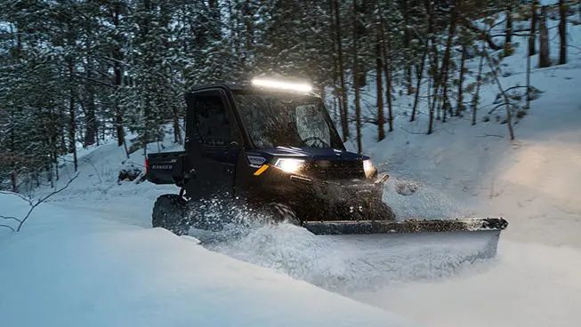 A Polaris RANGER 1000 UTV plowing snow in the winter.