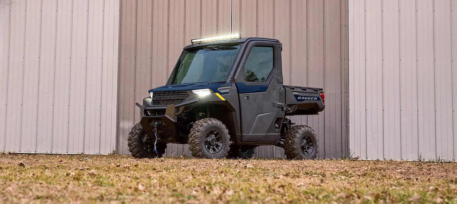 Side profile of a Polaris RANGER 1000 CAB UTV with illuminated for lights.