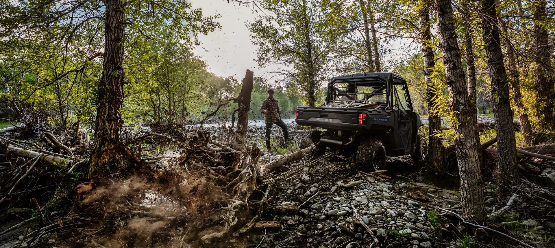 A Polaris RANGER 1000 UTV pulling out tree roots with a chain attached to the rear hitch.
