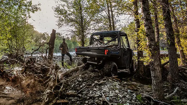 A Polaris RANGER 1000 UTV pulling out tree roots with a chain attached to the rear hitch.