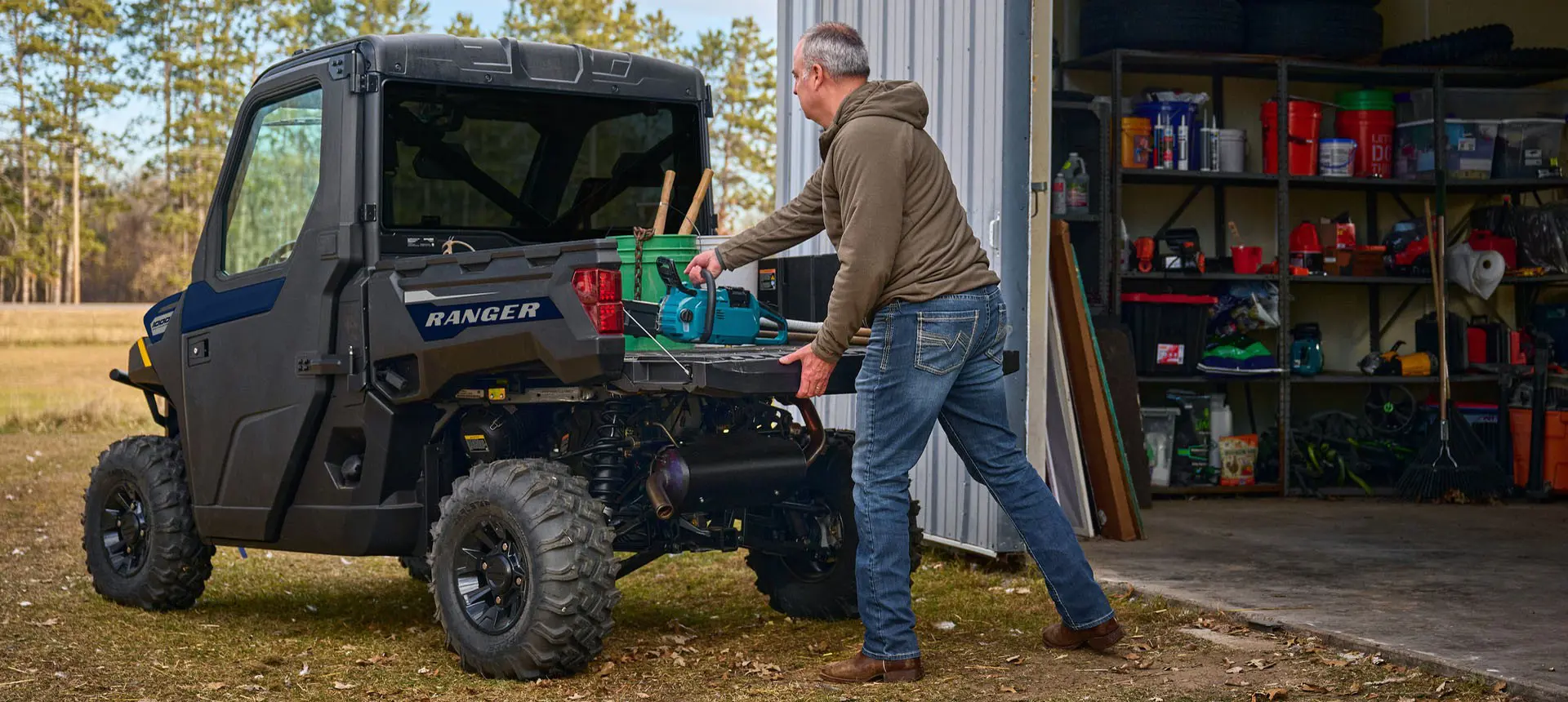 A man loading gear into the cargo box of his Polaris RANGER 1000 CAB enclosed UTV.