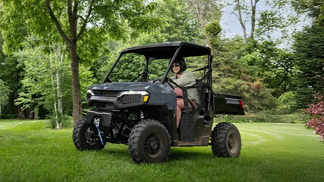 A person driving through their yard in a stealth gray Polaris RANGER 500 UTV.