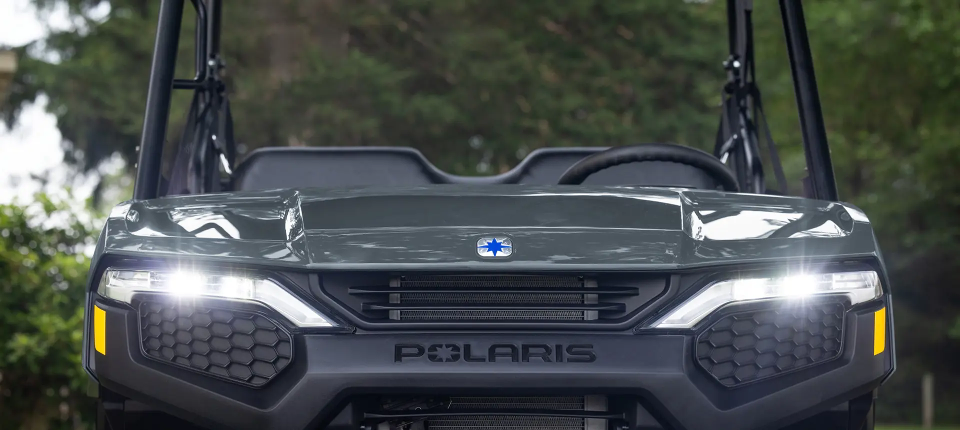 Front end view of a Polaris RANGER 500 utility vehicle with illuminated headlights.
