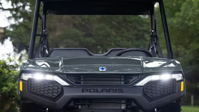 Front end view of a Polaris RANGER 500 utility vehicle with illuminated headlights.