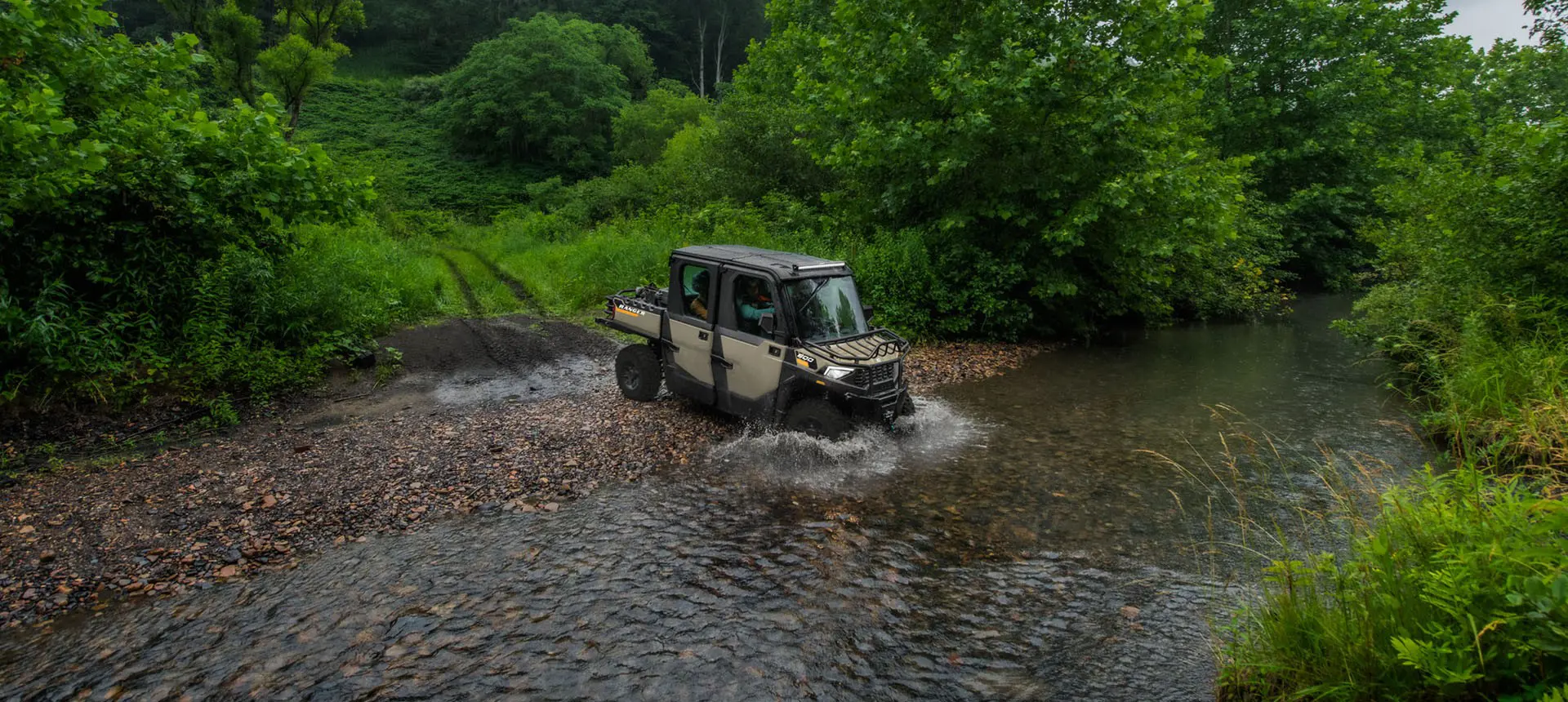 A Polaris RANGER CREW 600 NorthStar UTV driving through a shallow riverbed.