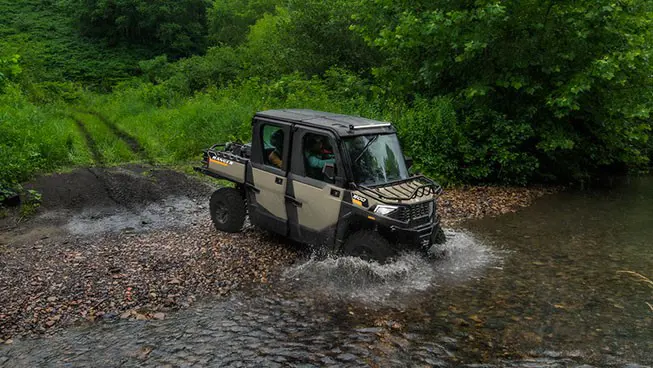 A Polaris RANGER CREW 600 NorthStar UTV driving through a shallow riverbed.