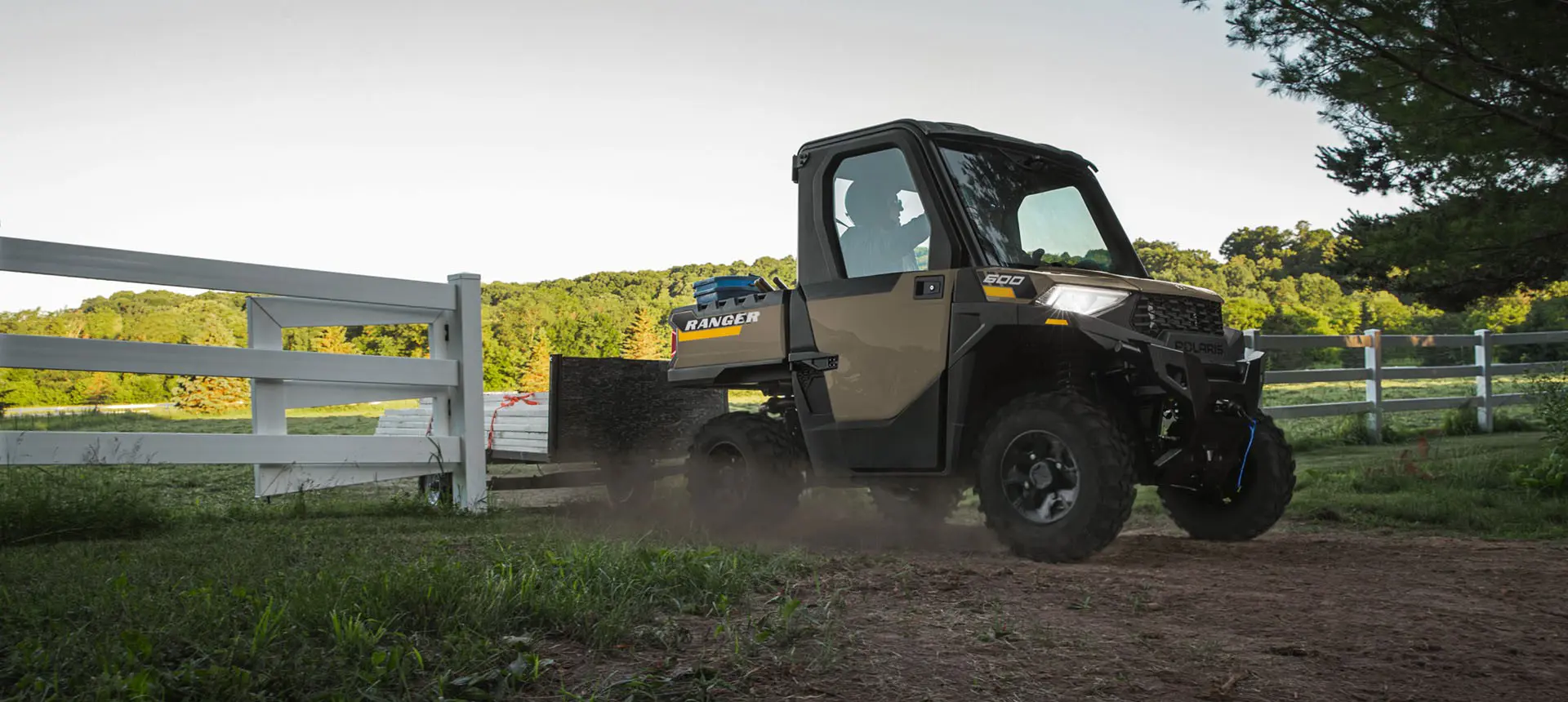 A Polaris RANGER 600 NorthStar UTV pulling a trailer on a farm.