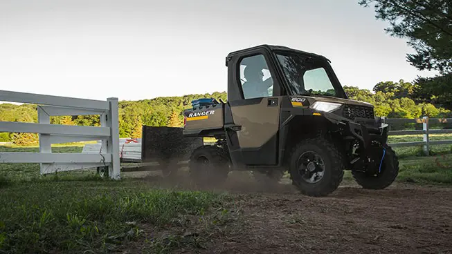 A Polaris RANGER 600 NorthStar UTV pulling a trailer on a farm.