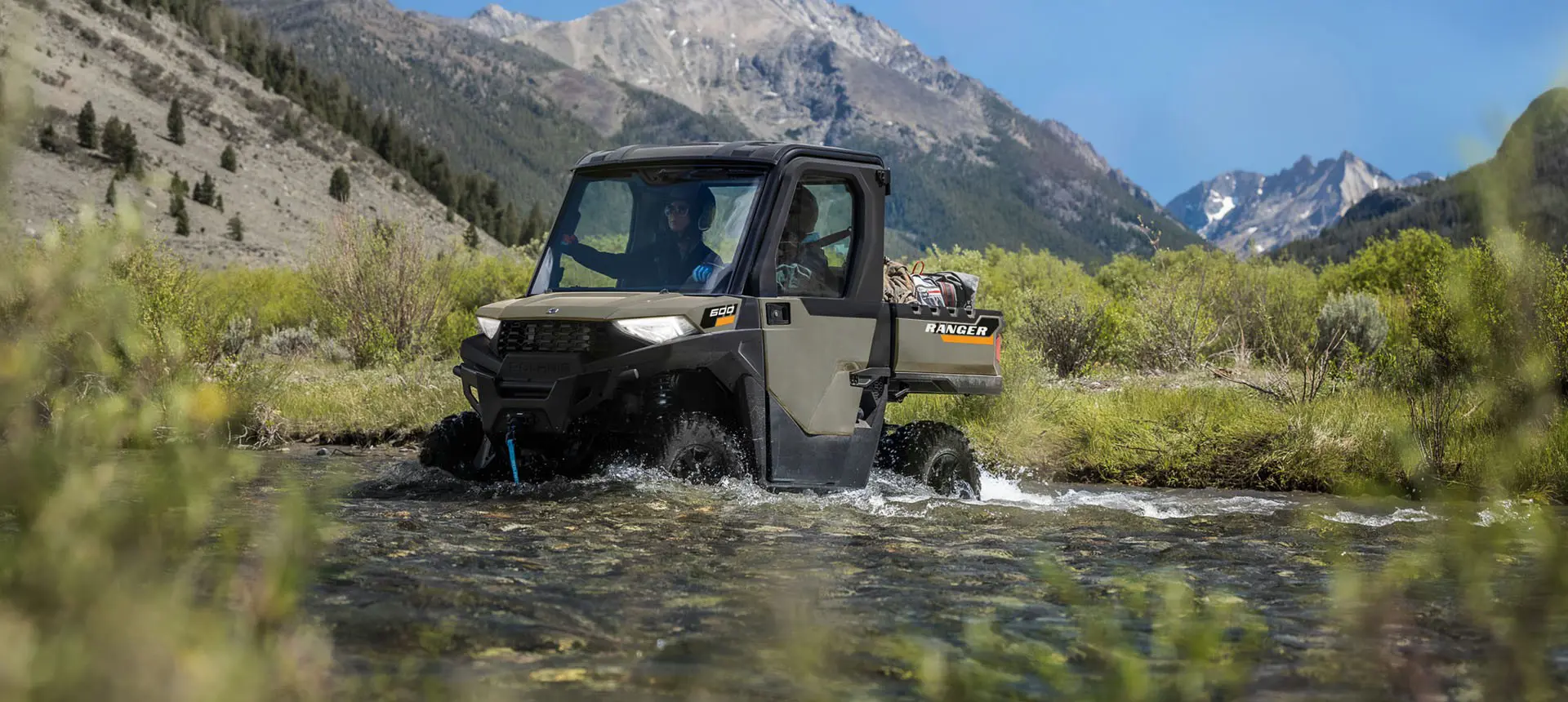 A Polaris RANGER 600 NorthStar UTV driving through a shallow stream.