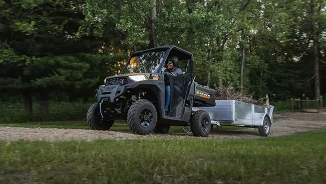 A Polaris RANGER 600 UTV pulling a trailer loaded with debris.