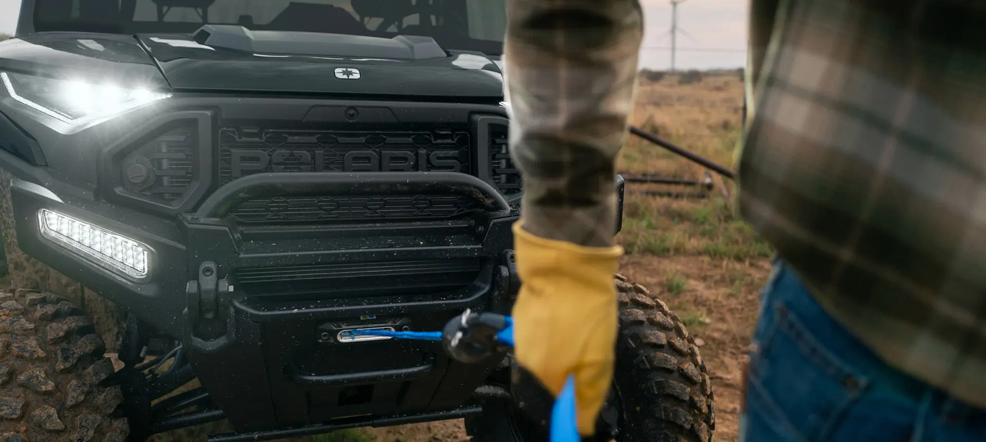 A person pulling out the winch from the front end of a Polaris RANGER XD 1500 NorthStar extreme duty UTV.