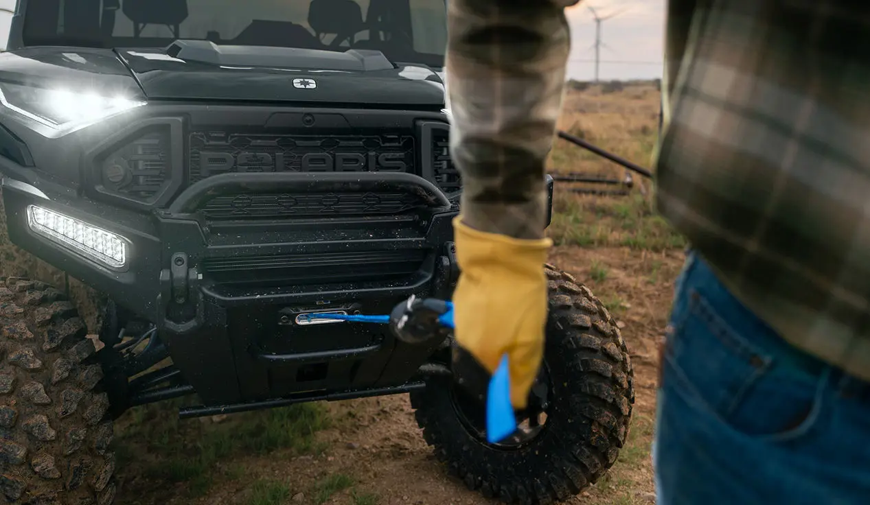A person pulling out the winch from the front end of a Polaris RANGER XD 1500 NorthStar extreme duty UTV.