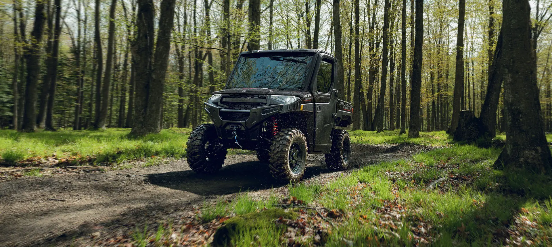 A Polaris RANGER XP 1000 NorthStar Trail Boss Edition UTV driving on a trail in the forest.