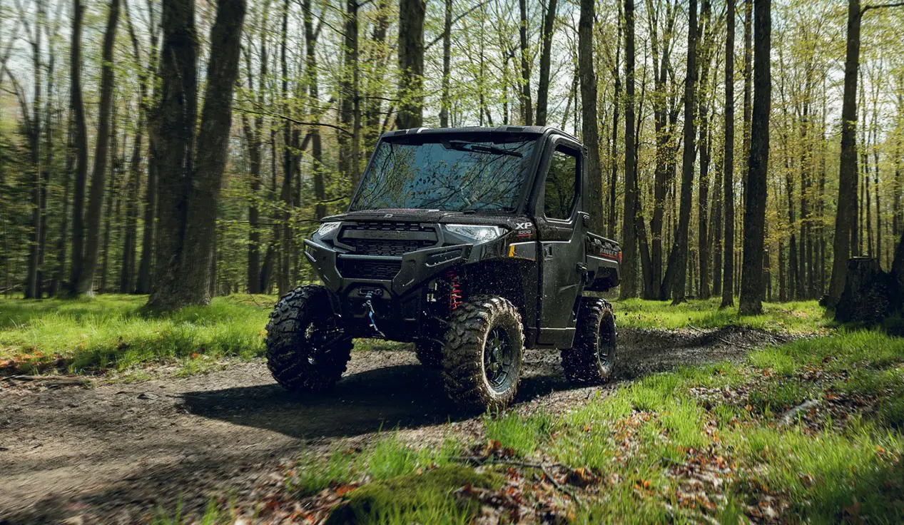 A Polaris RANGER XP 1000 NorthStar Trail Boss Edition UTV driving on a trail in the forest.
