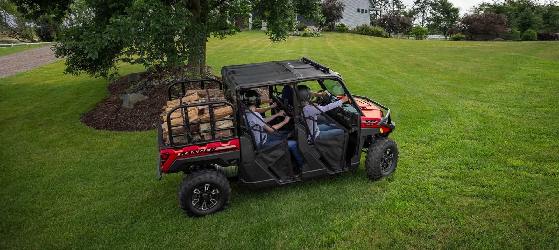 4 riders in a Polaris RANGER CREW XP 1000 UTV hauling wood in the cargo box.