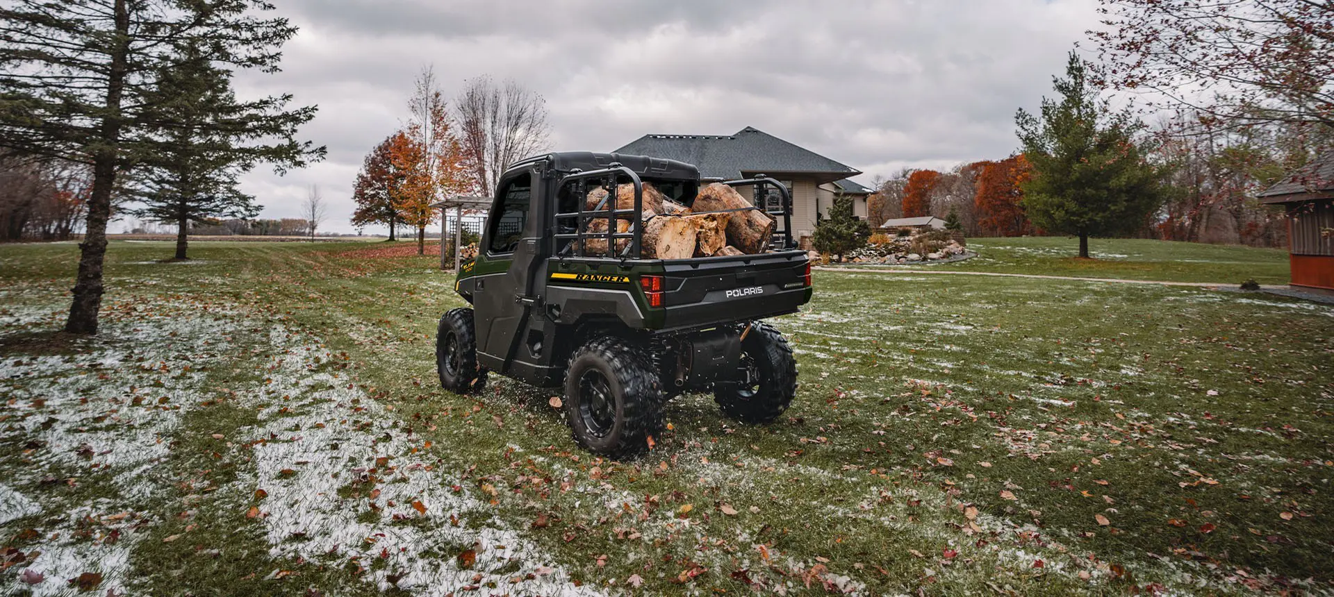 Rear-view of a Polaris RANGER XP 1000 NorthStar UTV hauling wood in the cargo box.
