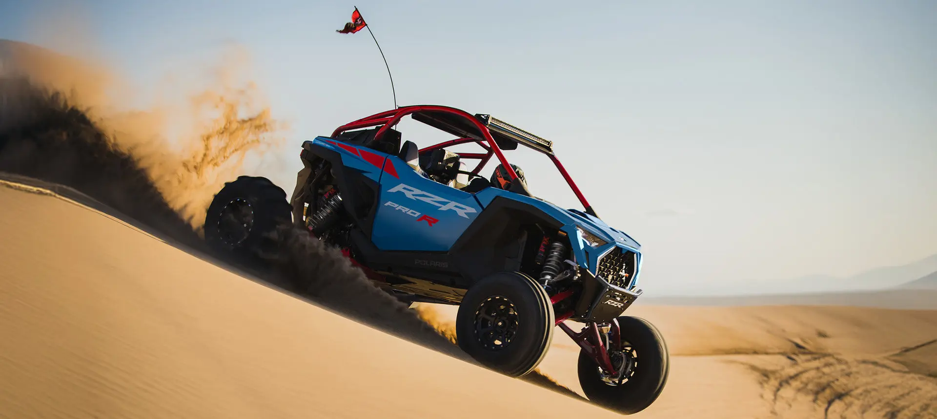 A Freedom Blue Polaris RZR Pro R side-by-side driving in the dunes.