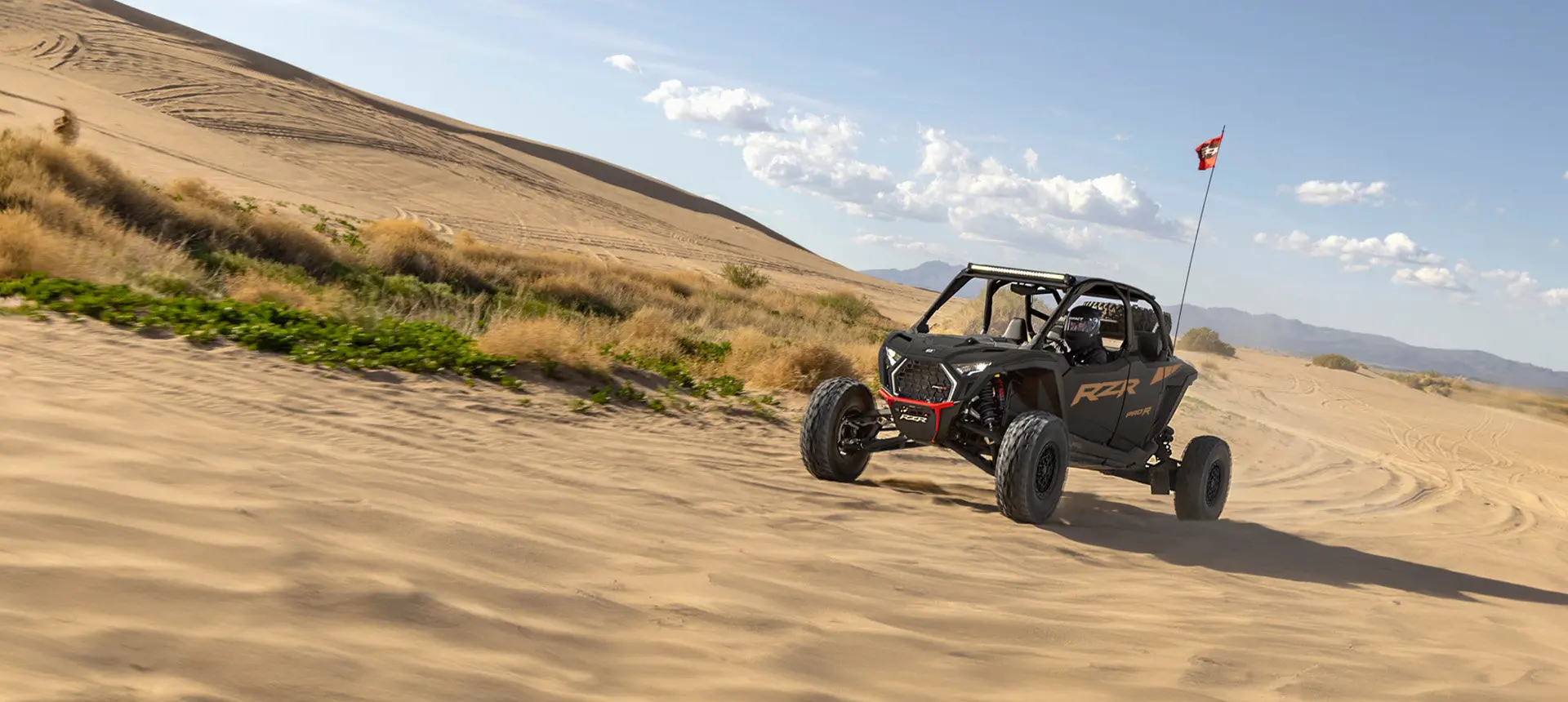 A Matte Super Graphite Polaris RZR Pro R side-by-side driving through the desert.
