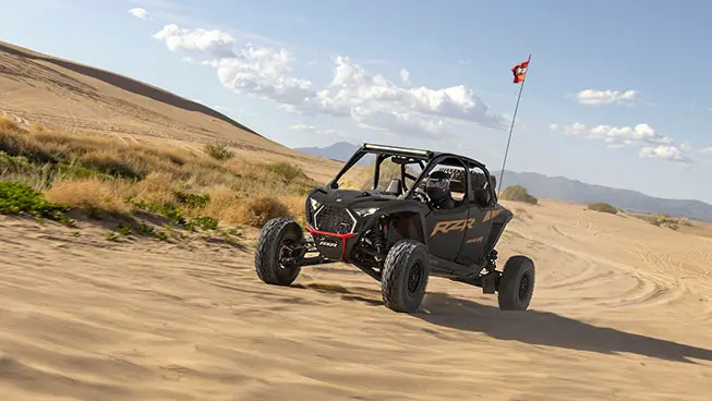 A Matte Super Graphite Polaris RZR Pro R side-by-side driving through the desert.