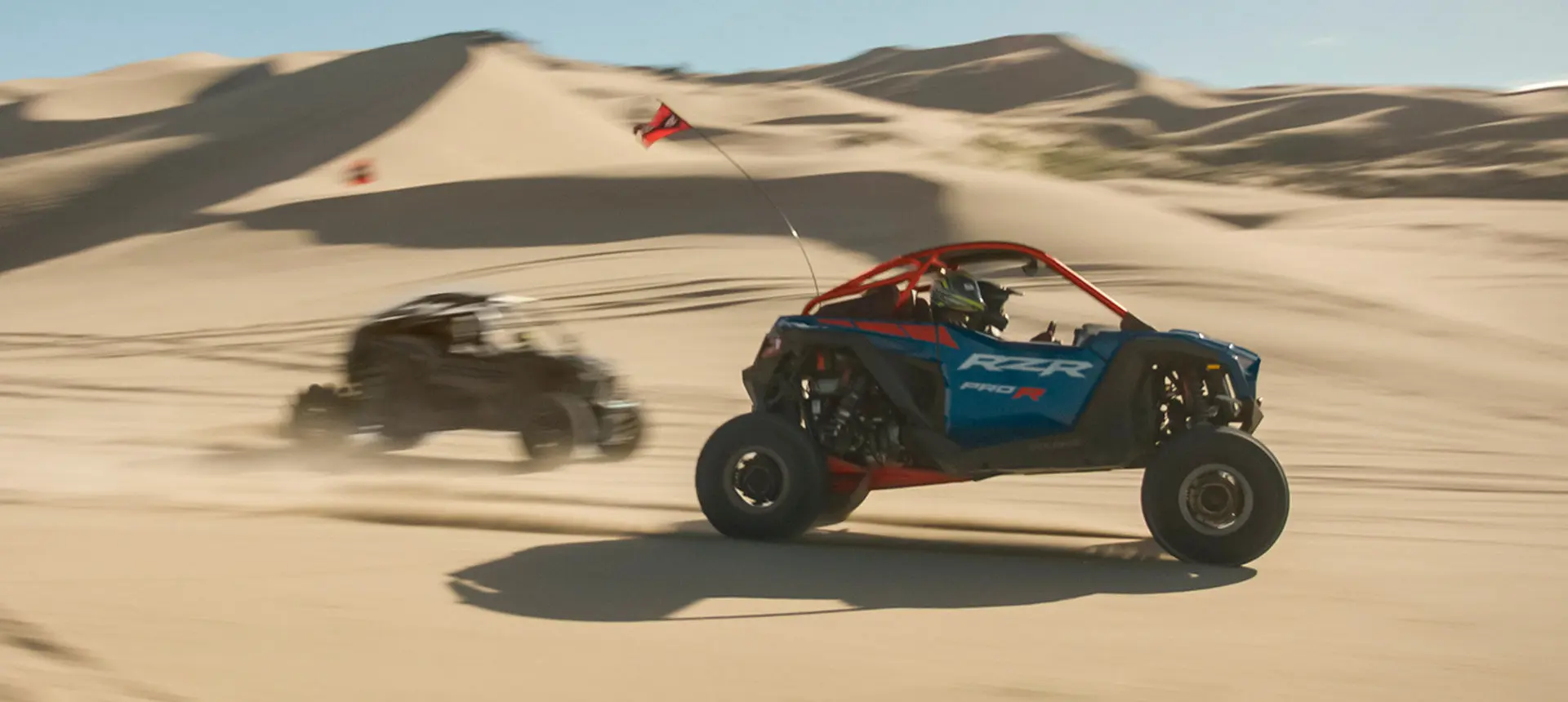 2 Polaris RZR Pro R side-by-sides driving through the desert.