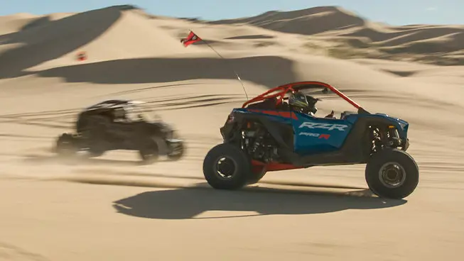2 Polaris RZR Pro R side-by-sides driving through the desert.