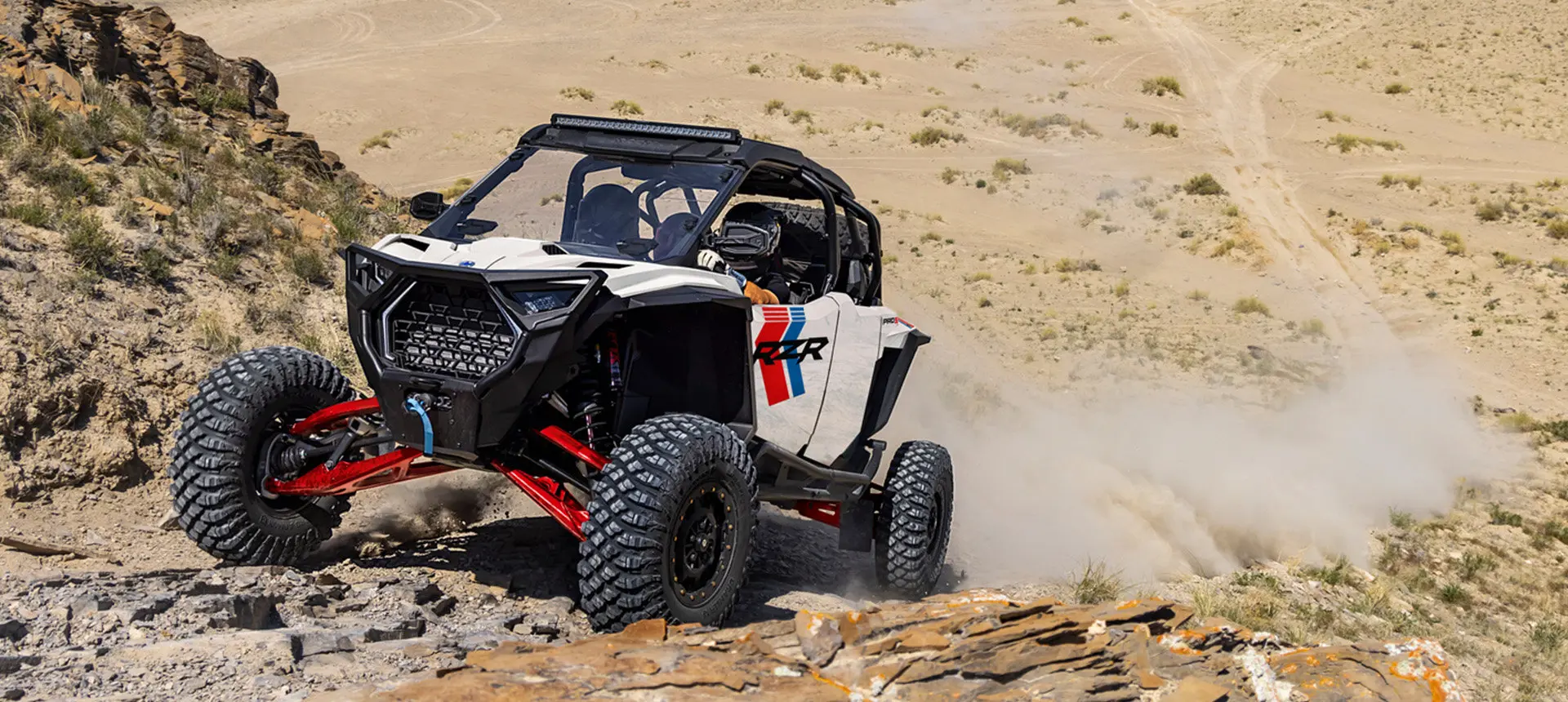 Polaris RZR Pro S side-by-side climbing over rocky terrain.