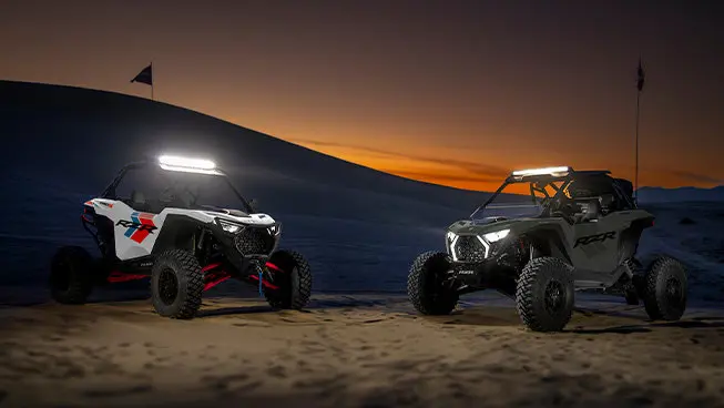 2 Polaris RZR Pro S side-by-sides with headlights illuminated.