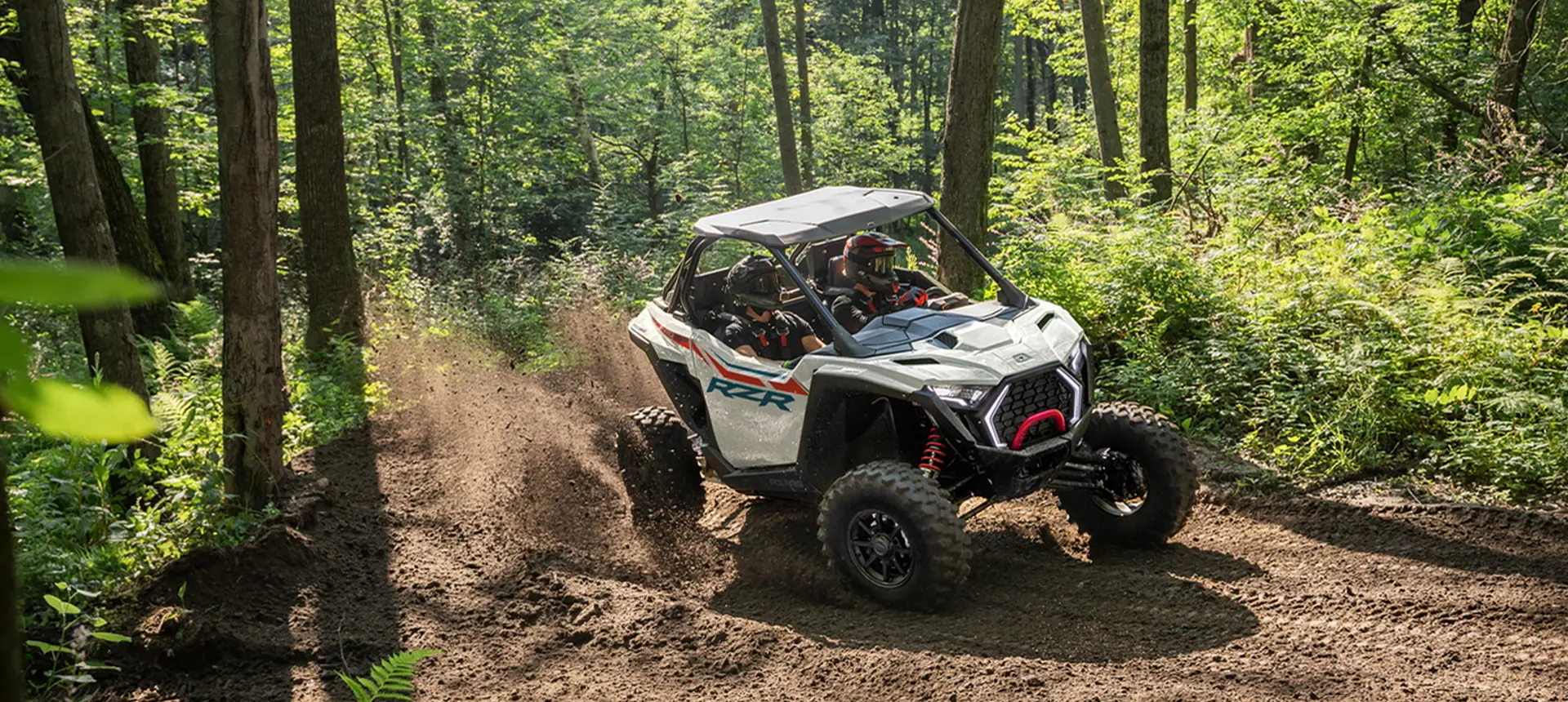 A Polaris RZR Pro XP side-by-side cruising on a forest trail.